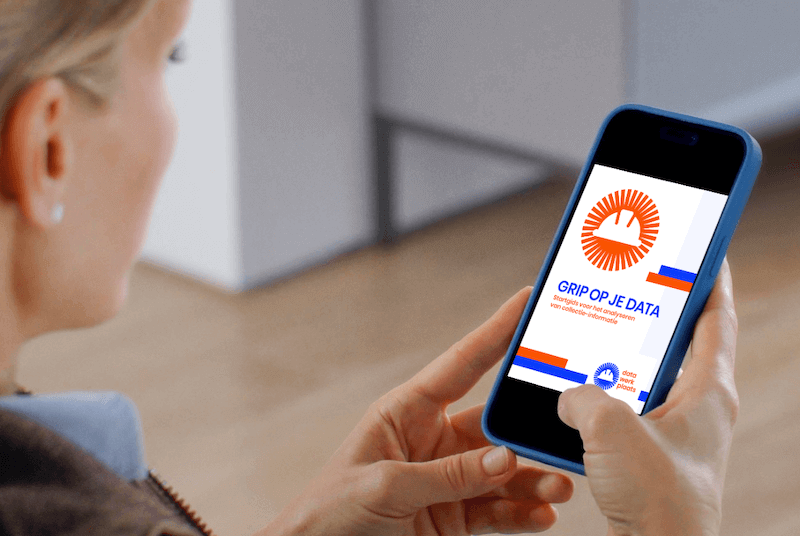 Vrouw met een mobieltje in haar hand met op het openingsscherm het omslag van Grip op je data