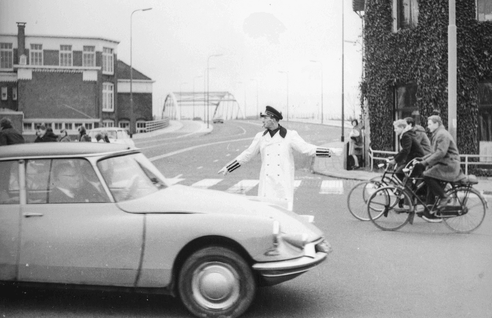 Verkeersagent bij een viaduct met een Citroën DS die komt aanrijden