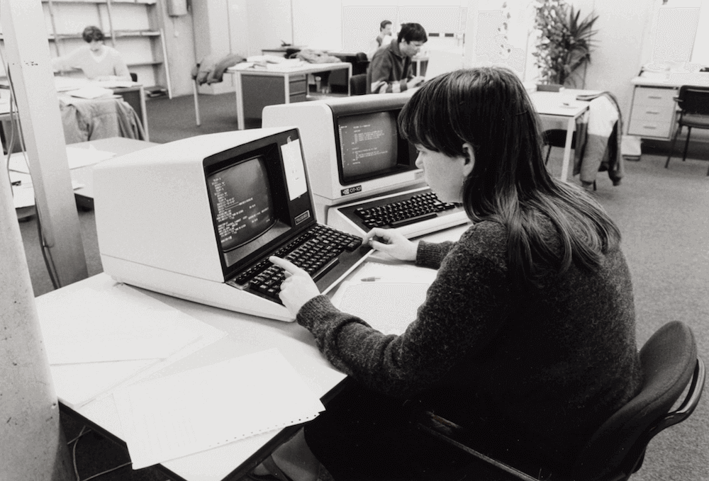 In een kantoortuin zit een vrouwelijke computerprogrammeur achter een bureau met een computer