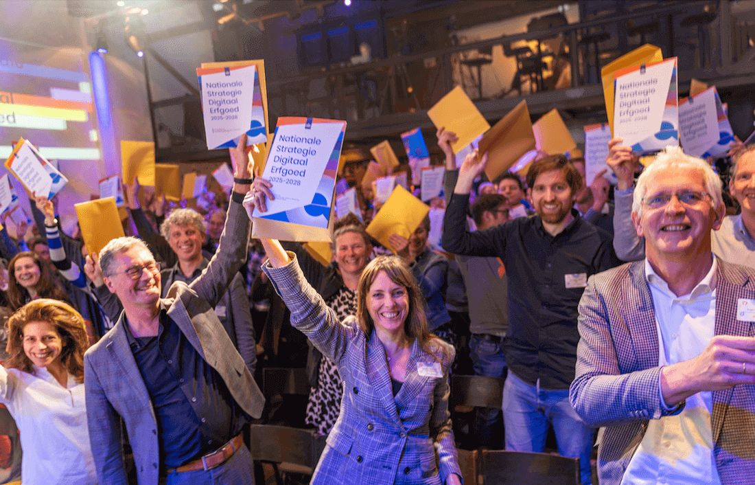 groep mensen die allemaal de papieren versie van de Nationale strategie Digitaal Erfgoed omhoog houden