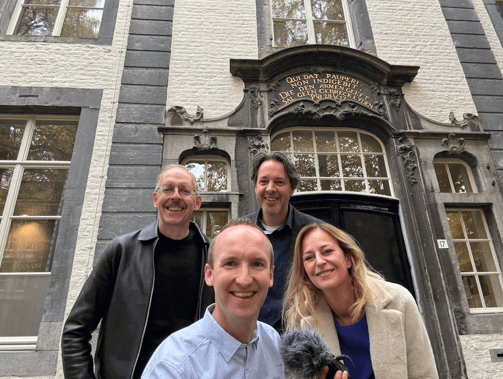 Vier mensen staan voor het oude gebouw van de universiteitsbibliotheek Maastricht.