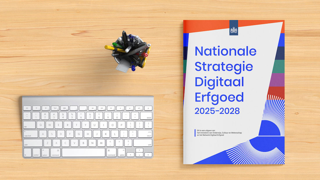 Bovenaanzicht van bureaublad met toetsenbord, pennen in bakje en papieren versie Nationale Strategie Digitaal Erfgoed